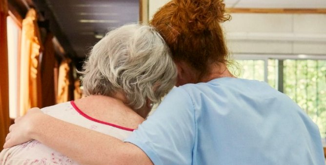A caregiver embracing an older woman